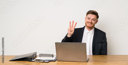 Businessman in a office happy and counting three with fingers