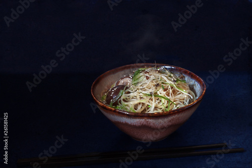 Bowl of Asian food: white hot  steam funchoza with shiitake mushroom soup on dark background photo