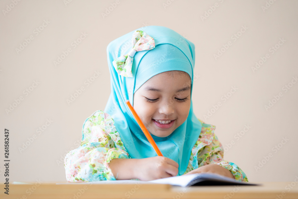Muslim kid doing homework and reading a book. Kid enjoy learning with happiness at home. Clever,Education and smart learning concept. Muslim kid doing homework and reading a book. Kid enjoy learning with happiness at home. Clever,Education and smart learning concept.