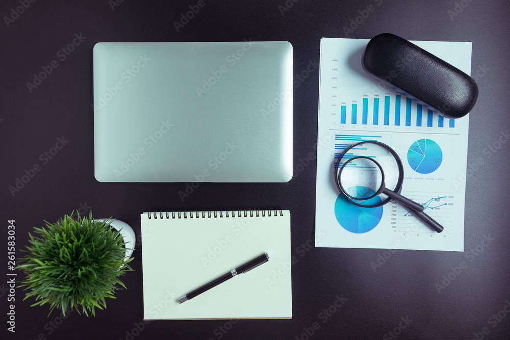 Top view, black desk with computer graph, magnifier and calculator Of businessmen in the office. Top view, black desk with computer graph, magnifier and calculator Of businessmen in the office.
