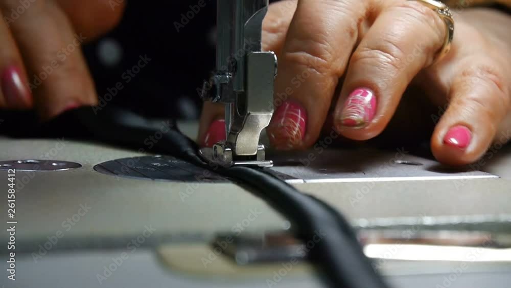Closeup of tailor. Female hands of a seamstress at work. Sewing with a sewing machine with black material. Fashion industry. Closeup of tailor. Female hands of a seamstress at work. Sewing with a sewing machine with black material. Fashion industry.