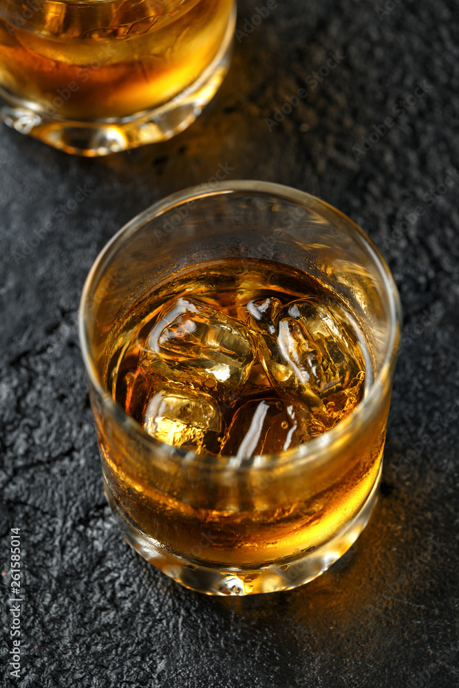 Glass of whiskey with ice on rustic background