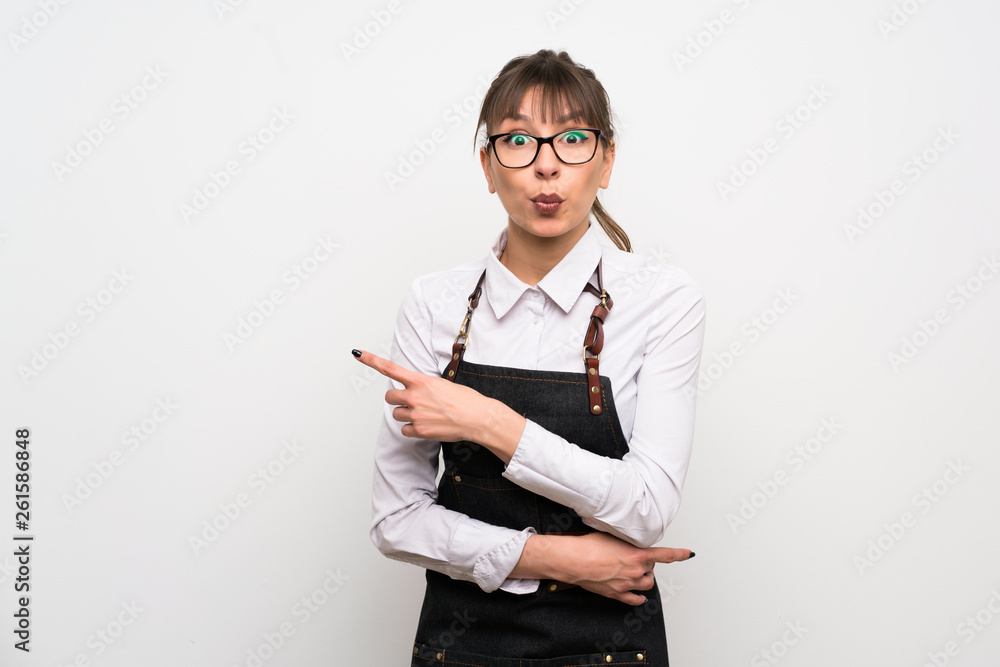 Young woman with apron surprised and pointing side Young woman with apron surprised and pointing side