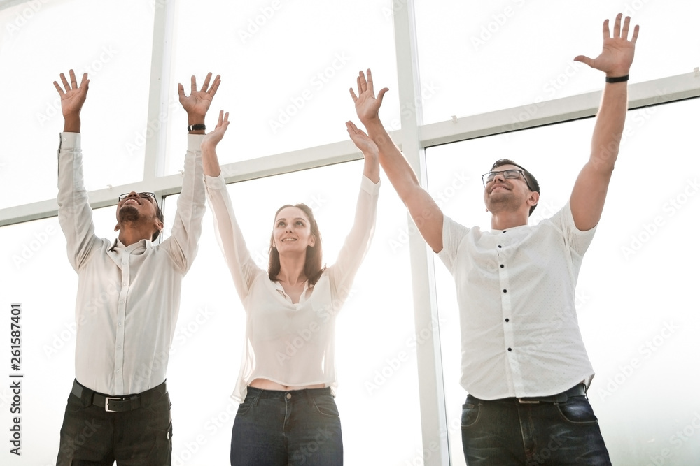 happy business team standing together and lifting their hands up. happy business team standing together and lifting their hands up.