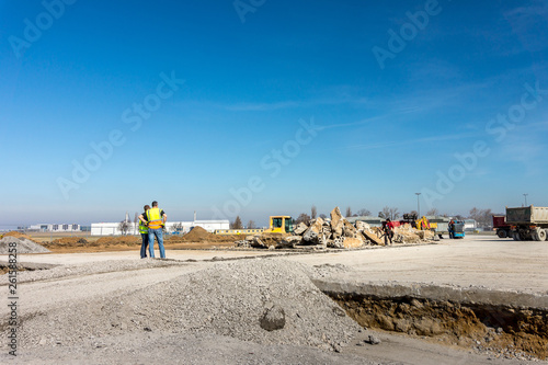 Construction site of road, building or airport with construction machinery (truck, bulldozer, excavator) and construction workers or engineers