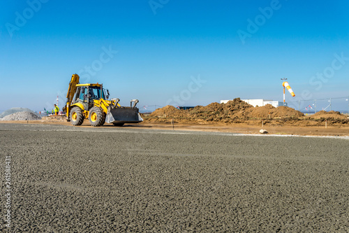 Construction site of road, building or airport with construction machinery (truck, bulldozer, excavator) and construction workers or engineers