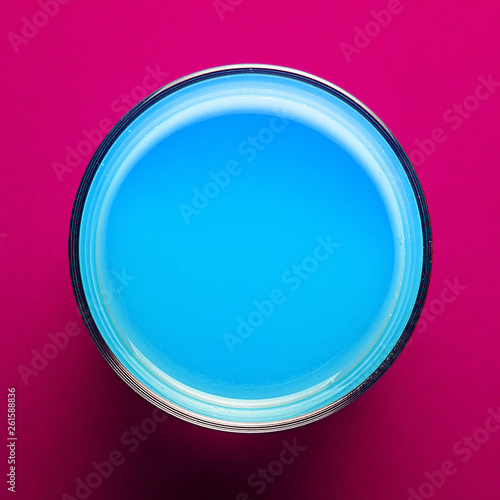 Creative template glass with blue paint on colored pink paper for text. Brochure concept.