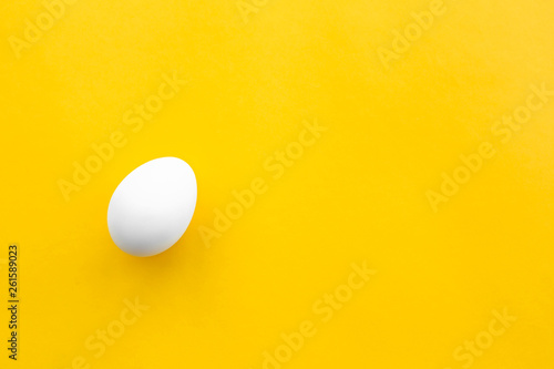 One white chicken egg lies on a yellow background. Healthy organic food and diet concept. Easter theme