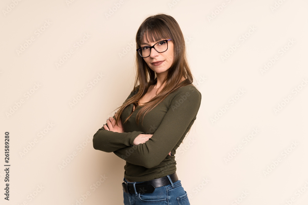 Young woman on ocher background with arms crossed and looking forward