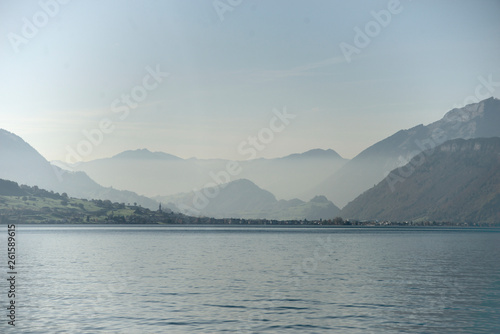 View across lake of lucerne. A village and mountain ranges in the background.