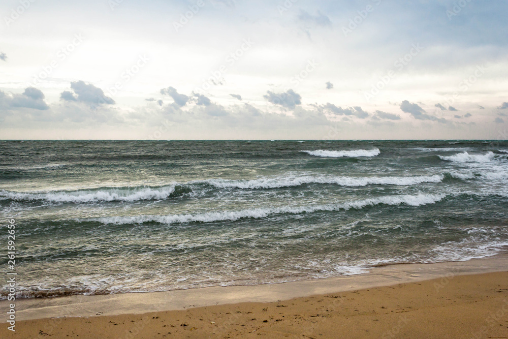 Blue and green waves with white foam on sandy beach. Black Sea, Evpatoria, Crimea, Russia. Travel, wacation concept. Text copy space.