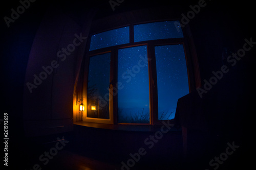 Night scene of stars seen through the window from dark room. Night sky inside dark room. Long exposure shot