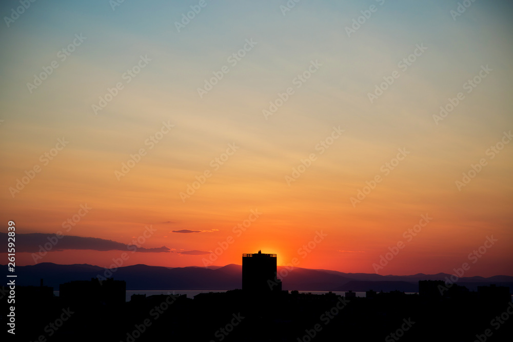 Beautiful orange sunset over a dark landscape in the silhouettes of the city
