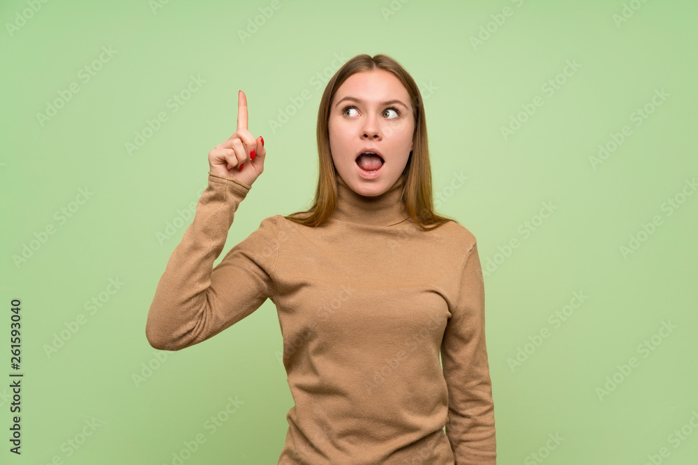 Young woman with turtleneck sweater intending to realizes the solution while lifting a finger up Young woman with turtleneck sweater intending to realizes the solution while lifting a finger up