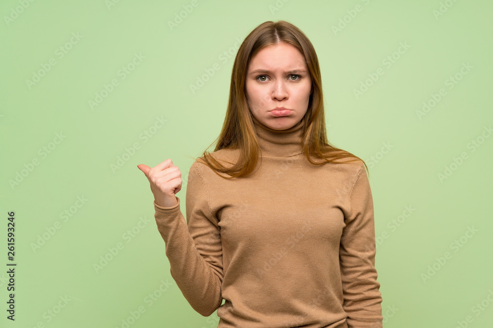 Young woman with turtleneck sweater unhappy and pointing to the side Young woman with turtleneck sweater unhappy and pointing to the side