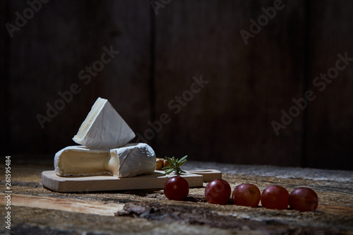 Layout of wineglass with grapes on wooden table with blue cheese