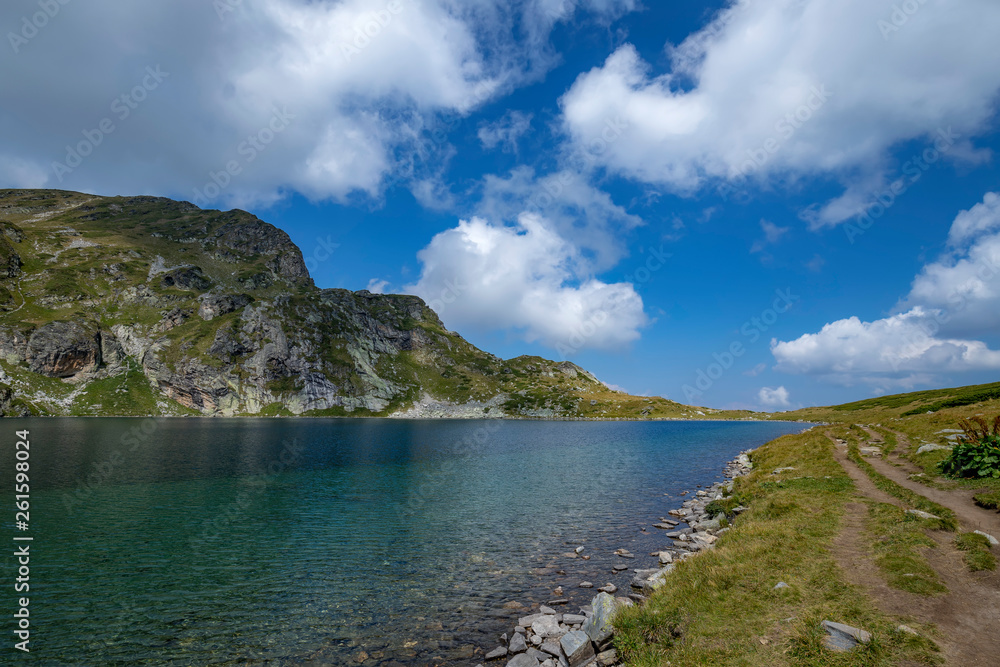 The natural landscape of mountain hill and beauty blue lake with a rough country road.