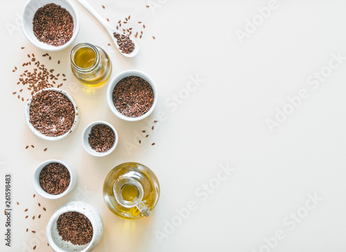flax seeds and flaxseed oil on white or light beige background. Set of small bowls with organic flax seed or linen seed. Flax oil is rich in omega-3 fatty acid. Copy space. Top view or flat-lay.