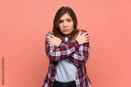 Young girl over pink wall freezing