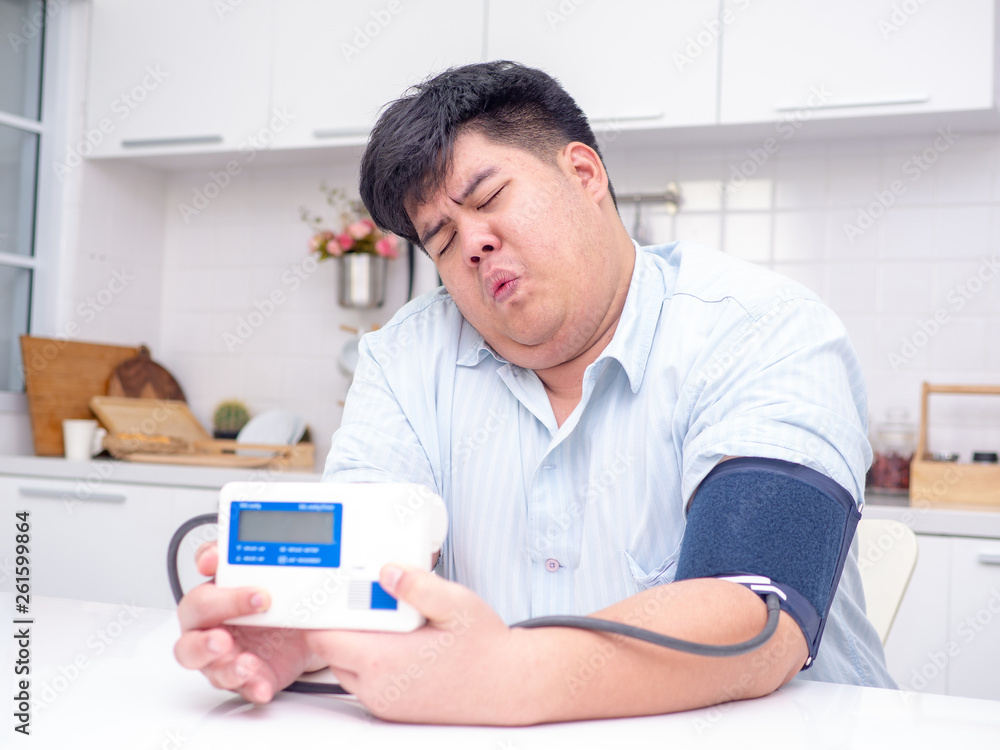 Asia fat man checking his pressure at home by self Asia fat man checking his pressure at home by self
