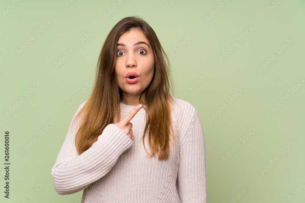 Obraz premium Young girl with white sweater pointing finger to the side and presenting a product