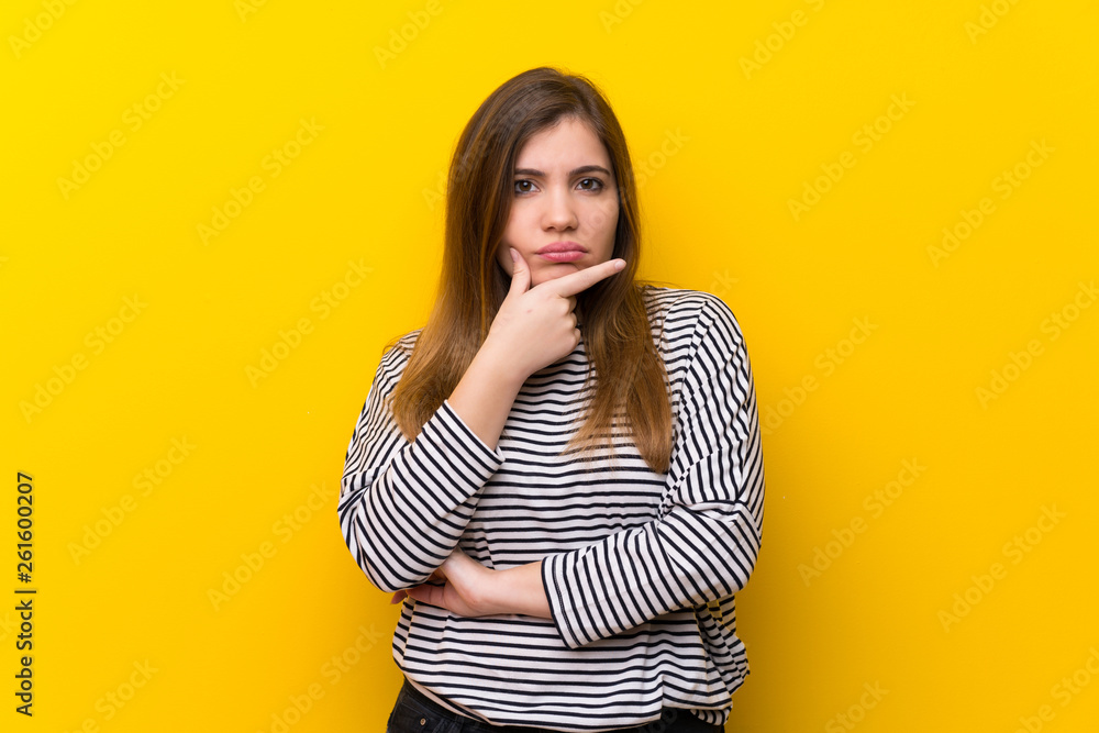 Young girl over yellow wall thinking Young girl over yellow wall thinking