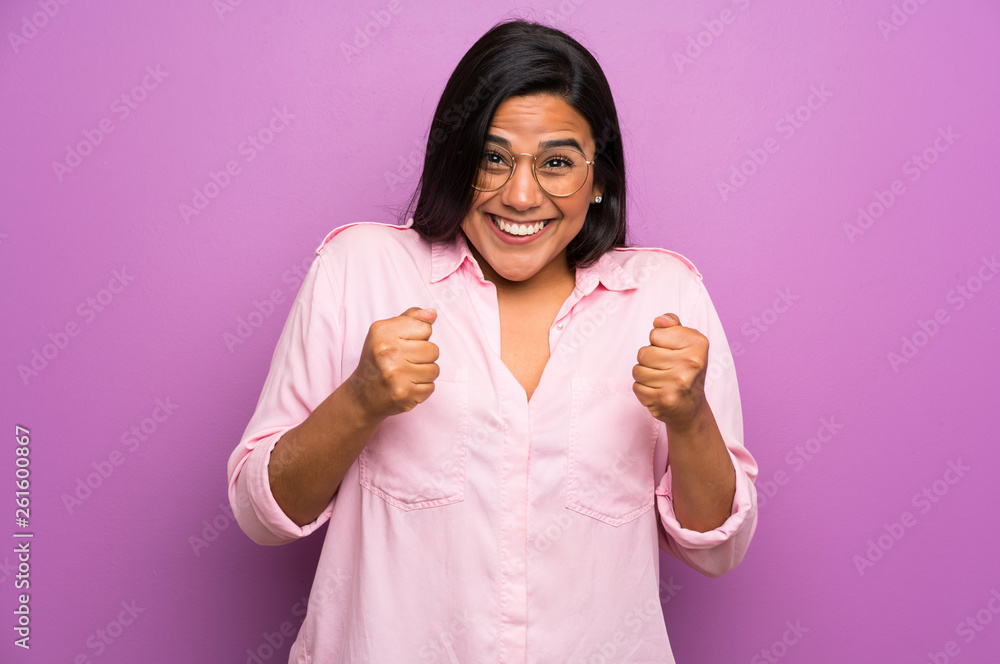 Young Colombian girl over purple wall celebrating a victory Young Colombian girl over purple wall celebrating a victory
