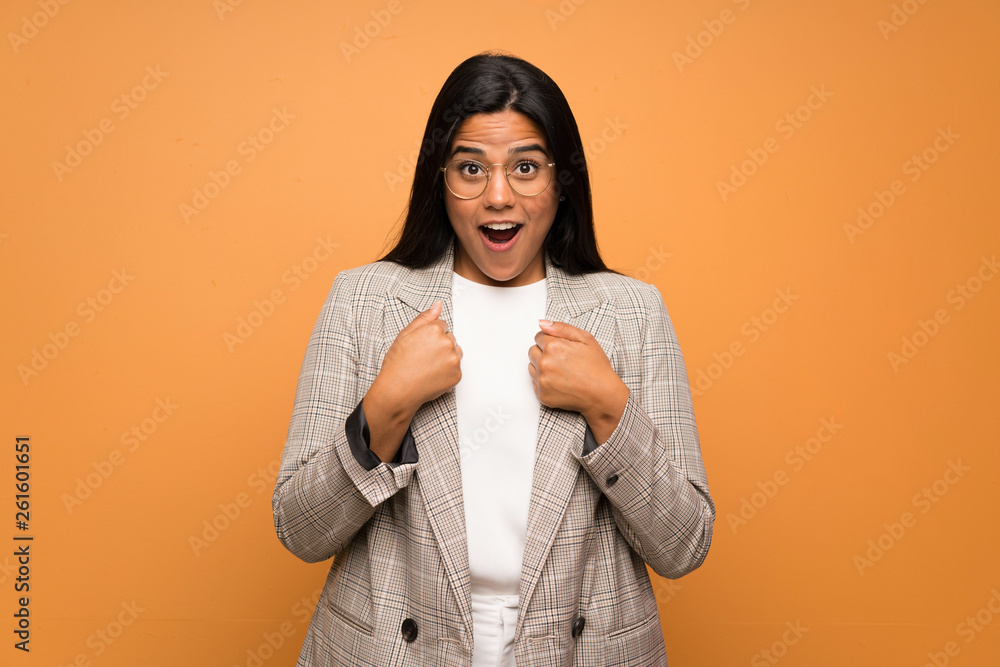 Young Colombian girl over brown wall with surprise facial expression Young Colombian girl over brown wall with surprise facial expression