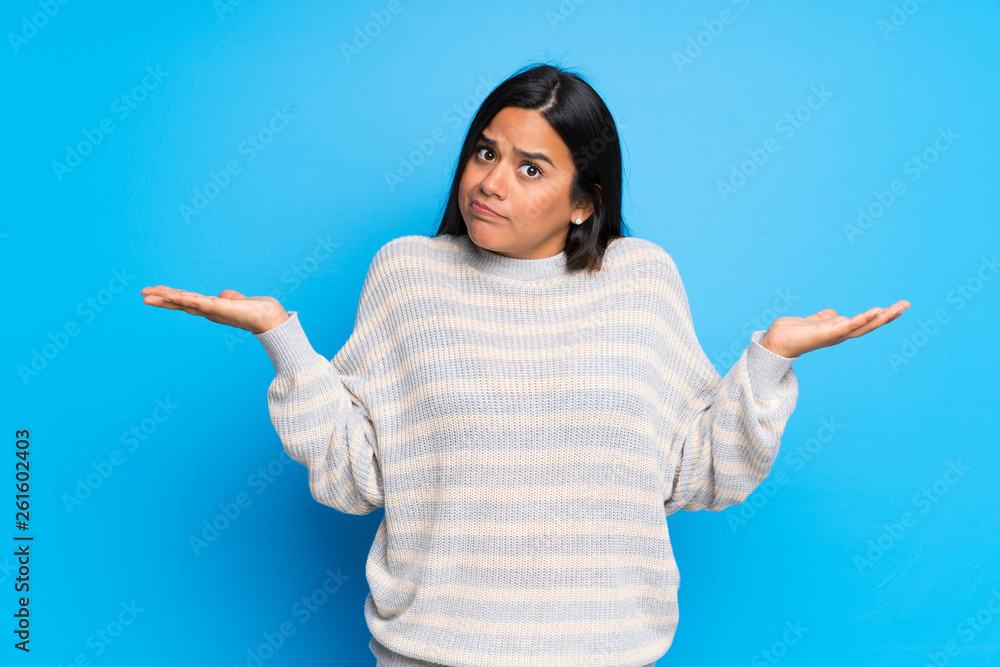Young Colombian girl with sweater having doubts while raising hands and shoulders Young Colombian girl with sweater having doubts while raising hands and shoulders
