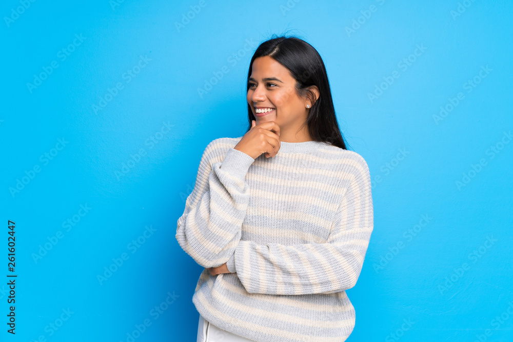 Young Colombian girl with sweater looking to the side with the hand on the chin Young Colombian girl with sweater looking to the side with the hand on the chin
