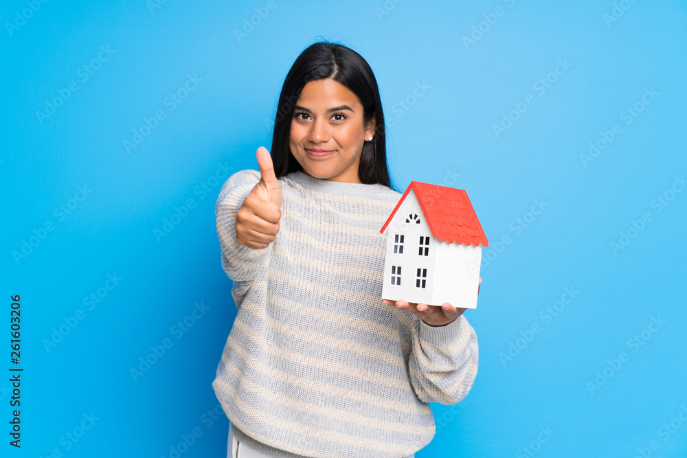 Young Colombian girl with sweater holding a little house Young Colombian girl with sweater holding a little house