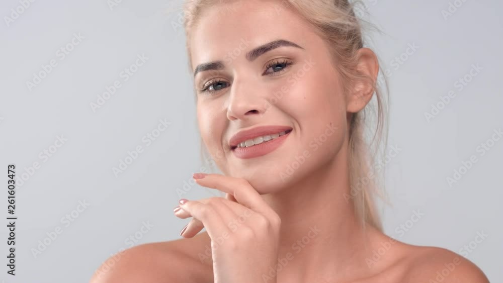 Blonde woman gently strokes her smooth face skin