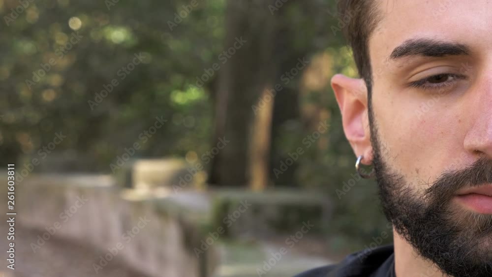 attractive young man opening his closed eye in the park.Half face attractive young man opening his closed eye in the park.Half face