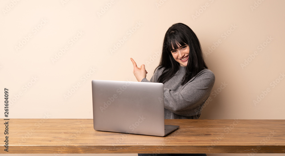 Young woman working with her laptop pointing back Young woman working with her laptop pointing back