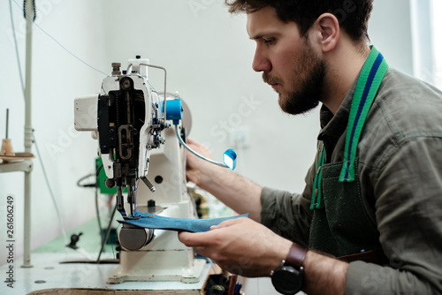 A master sews parts on a sewing machine for a future product made of genuine leather