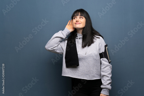 Young sport woman listening to something by putting hand on the ear