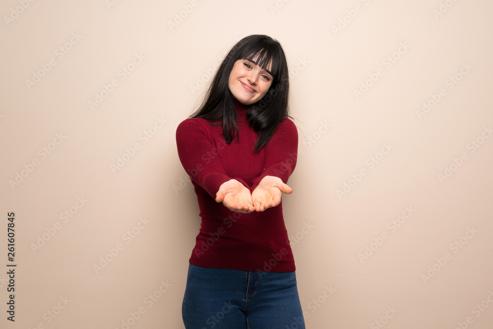 Young woman with red turtleneck holding copyspace imaginary on the palm to insert an ad Young woman with red turtleneck holding copyspace imaginary on the palm to insert an ad