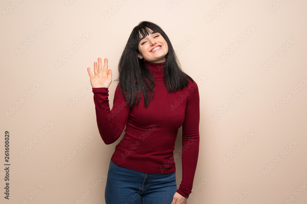 Young woman with red turtleneck saluting with hand with happy expression Young woman with red turtleneck saluting with hand with happy expression