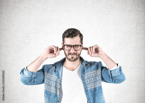 Young man in glasses covering ears
