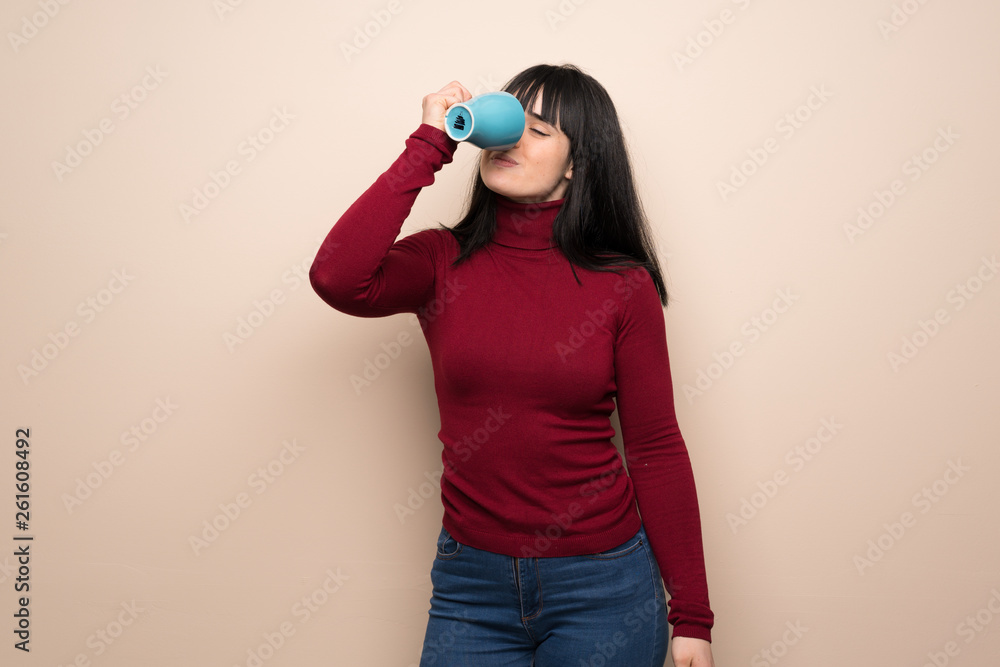 Young woman with red turtleneck holding a hot cup of coffee Young woman with red turtleneck holding a hot cup of coffee