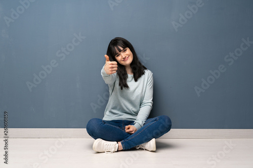 Woman sitting on the floor with thumbs up because something good has happened