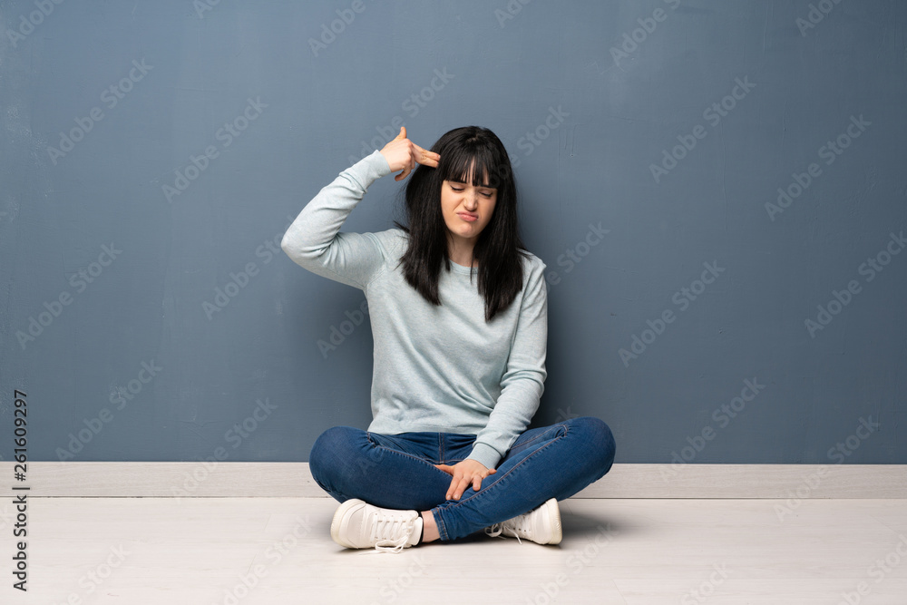 Woman sitting on the floor with problems making suicide gesture Woman sitting on the floor with problems making suicide gesture