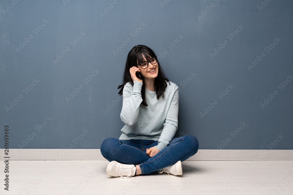 Woman sitting on the floor keeping a conversation with the mobile phone Woman sitting on the floor keeping a conversation with the mobile phone
