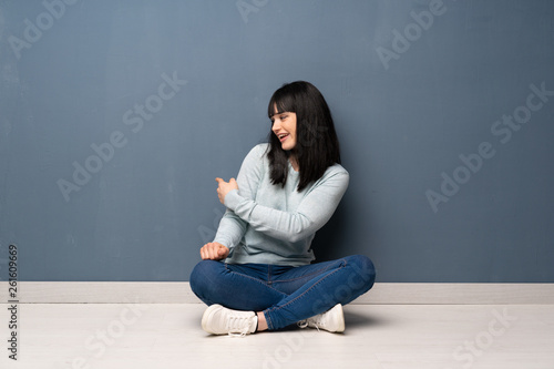 Woman sitting on the floor pointing back