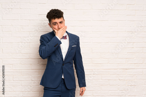 Man in suit and bow tie covering mouth with hands