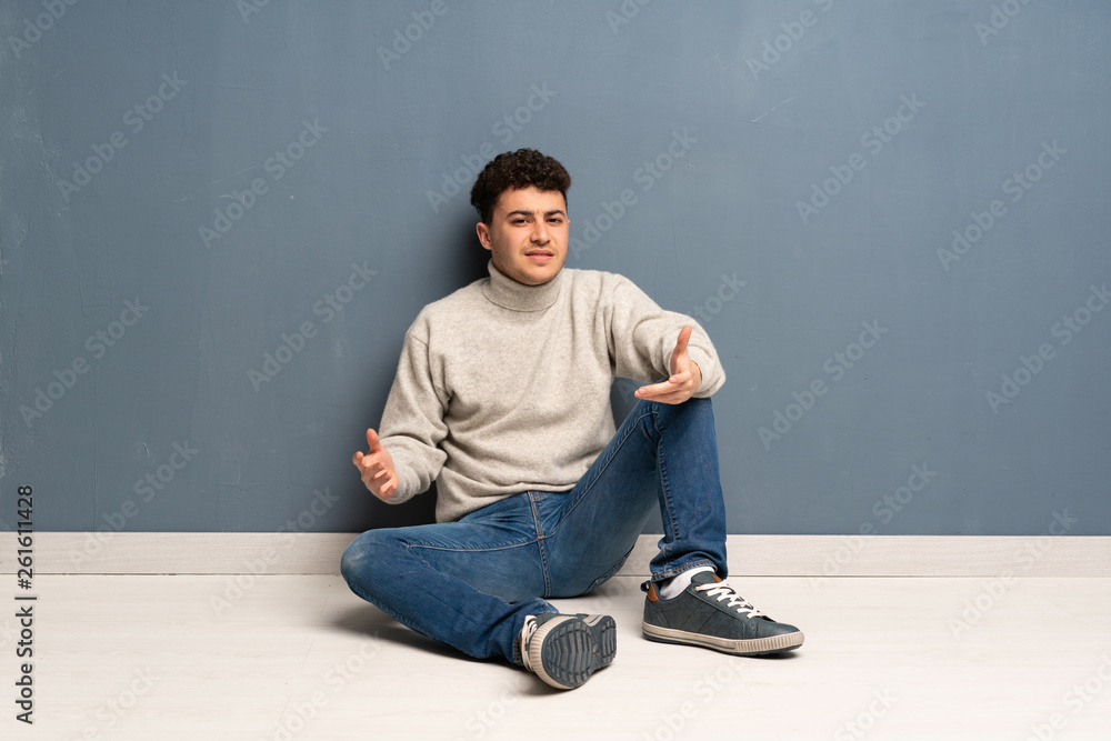 Young man sitting on the floor having doubts Young man sitting on the floor having doubts