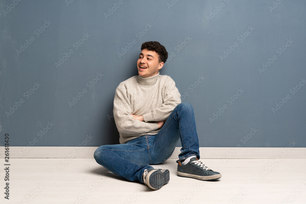 Young man sitting on the floor happy and smiling Young man sitting on the floor happy and smiling