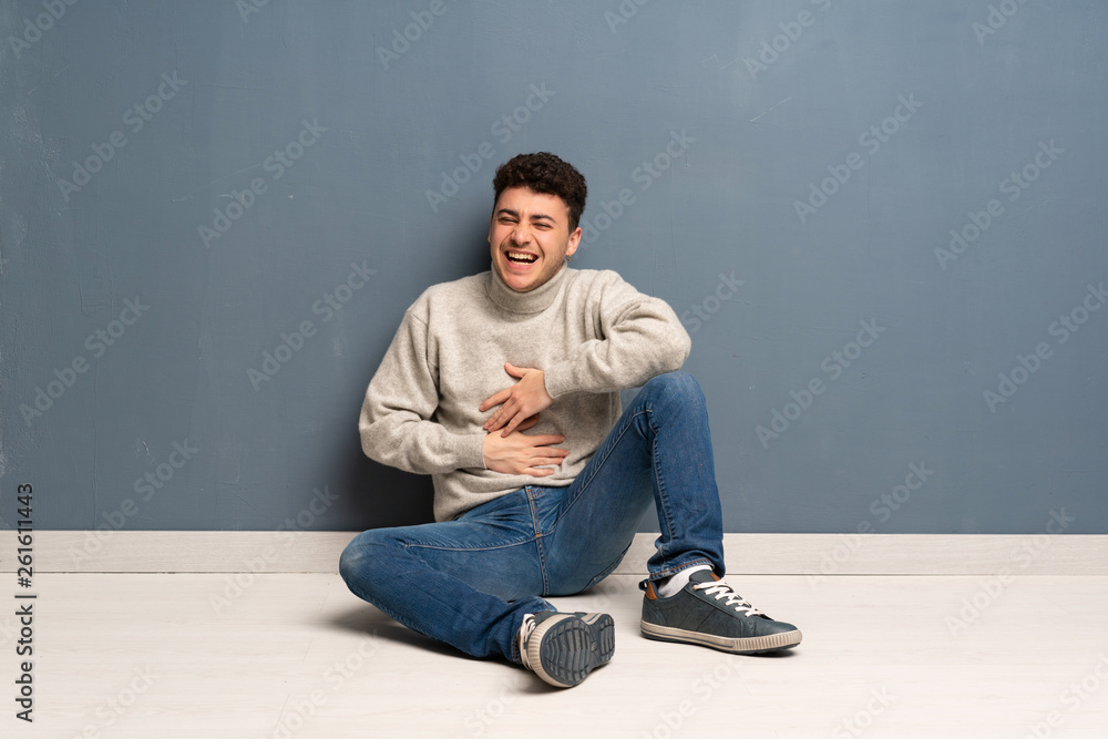 Young man sitting on the floor smiling a lot Young man sitting on the floor smiling a lot