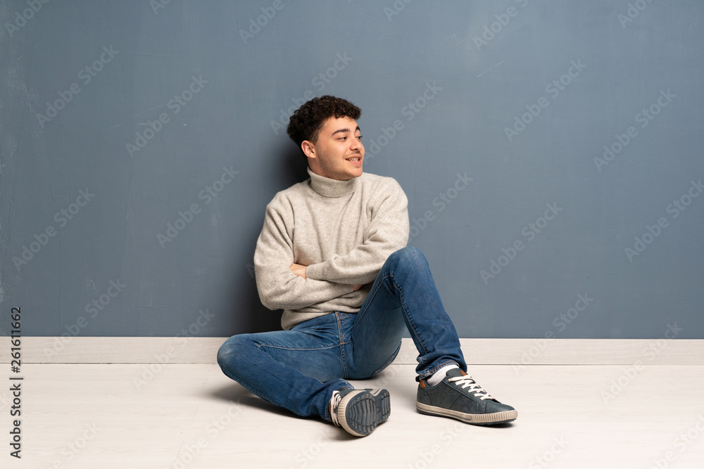 Young man sitting on the floor with arms crossed and happy Young man sitting on the floor with arms crossed and happy