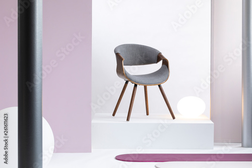 Fototapeta Naklejka Na Ścianę i Meble -  Real photo of a simple, white and purple room interior with a gray chair on a podium